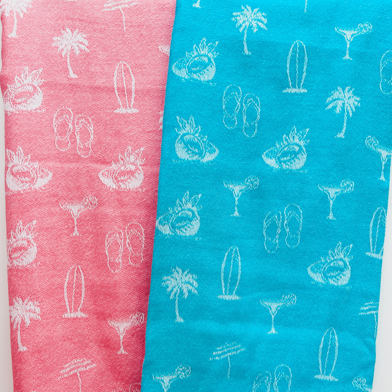 A pink and a blue towel both with palm trees, surfboards, coconuts, cocktails and flipflops on 