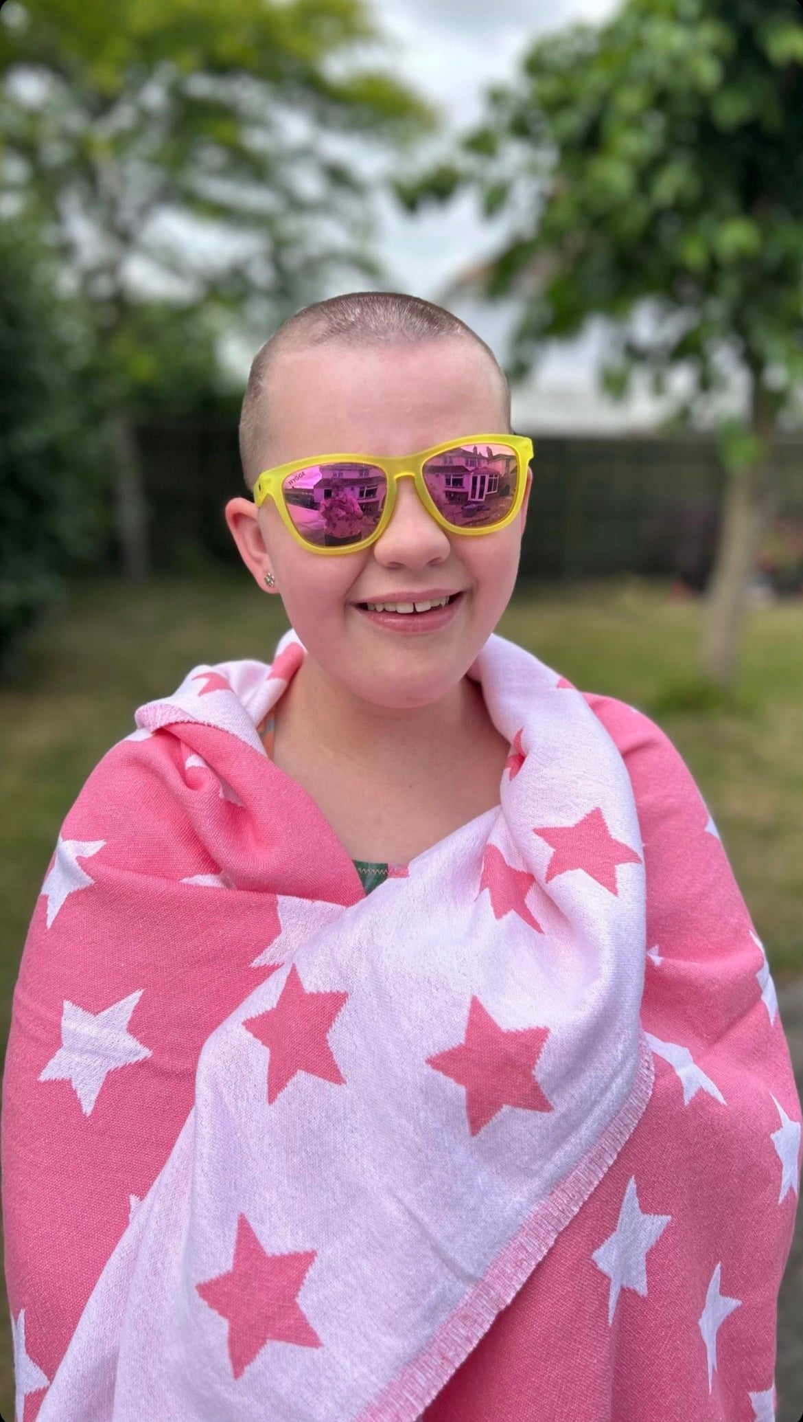 Lovely Tayen is smiling with her pink star towel wrapped round her and her yellow and purple pretty sunglasses
